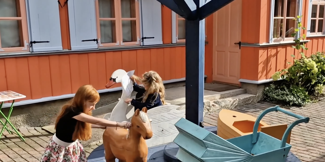 Lapsed mängivad Tartu Mänguasjamuuseumi õuealal vana lapsevankriga