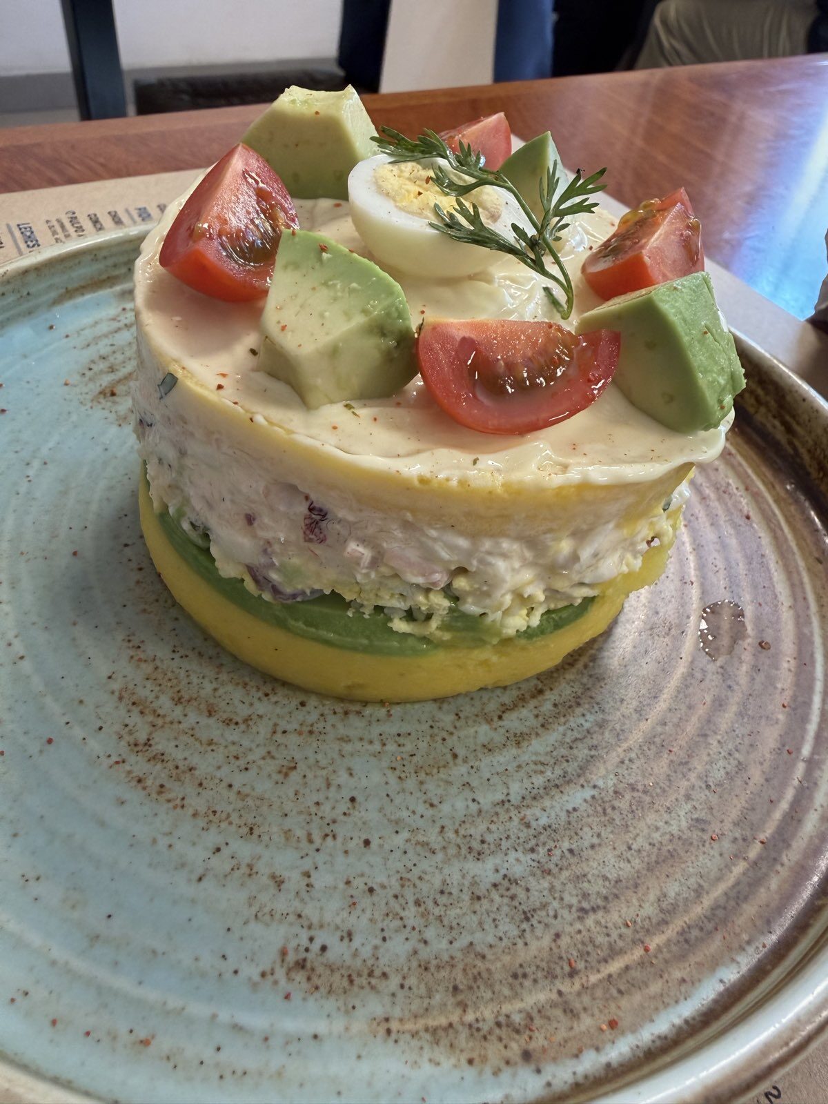 Pyöreä causa, päällä avokadoa, tomaattia ja kananmunaa