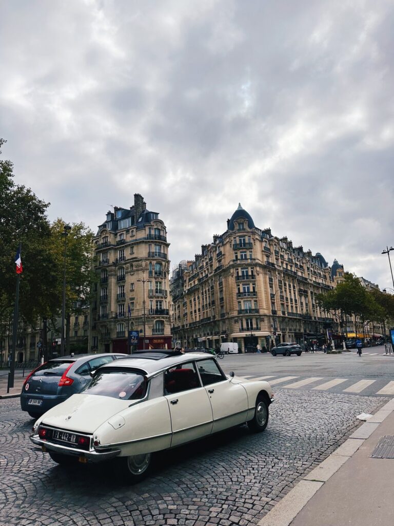 An old white Citroën on a Paris street under a cloudy sky