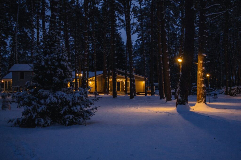 Mökki talvel männimetsas, aknad valgustatud