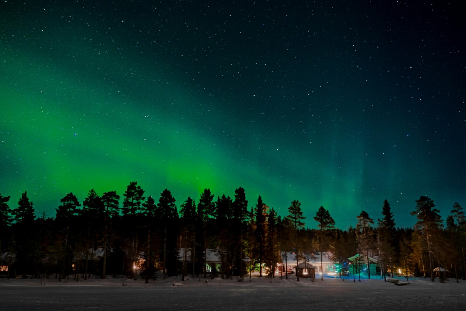 Uusaasta Soomes 2026: virmalised Lapimaa puhkeküla majade kohal